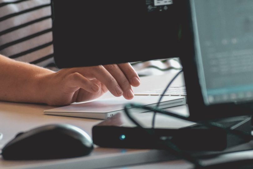 A person typing on a keyboard and using a mouse with a PC, relating to cybersecurity