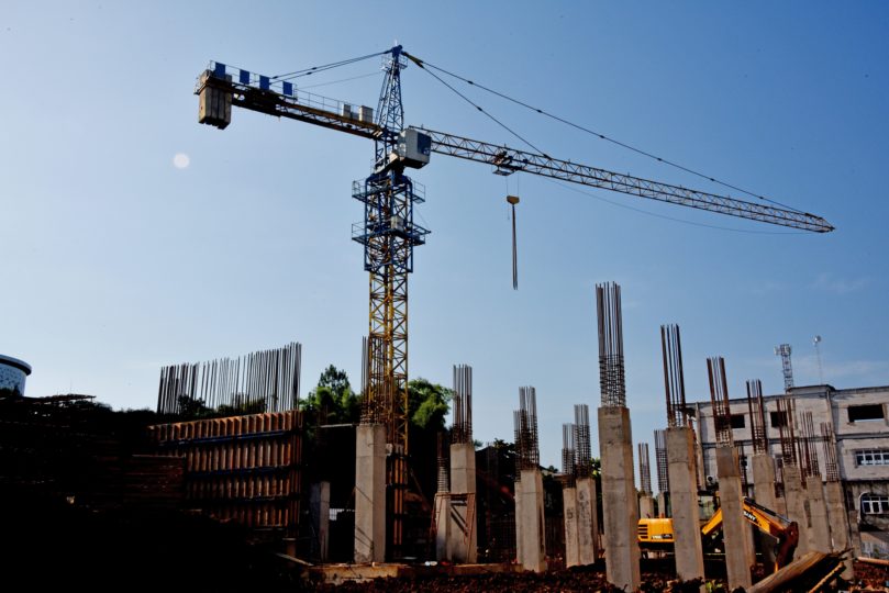 A crane, in blue skies, surrounded by construction